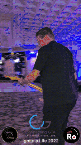 Guest posing with a prop on the 360 booth platform under blue event lighting
